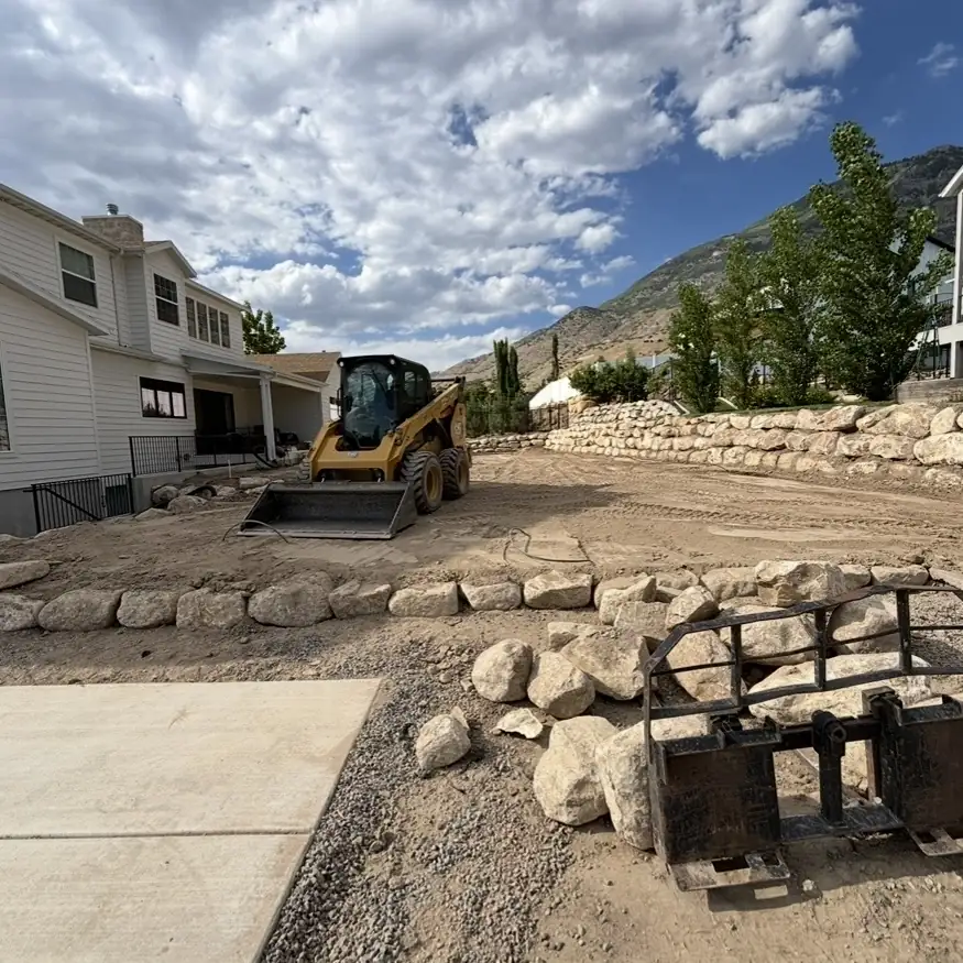 Tiered boulder retaining walls going in beside a new home