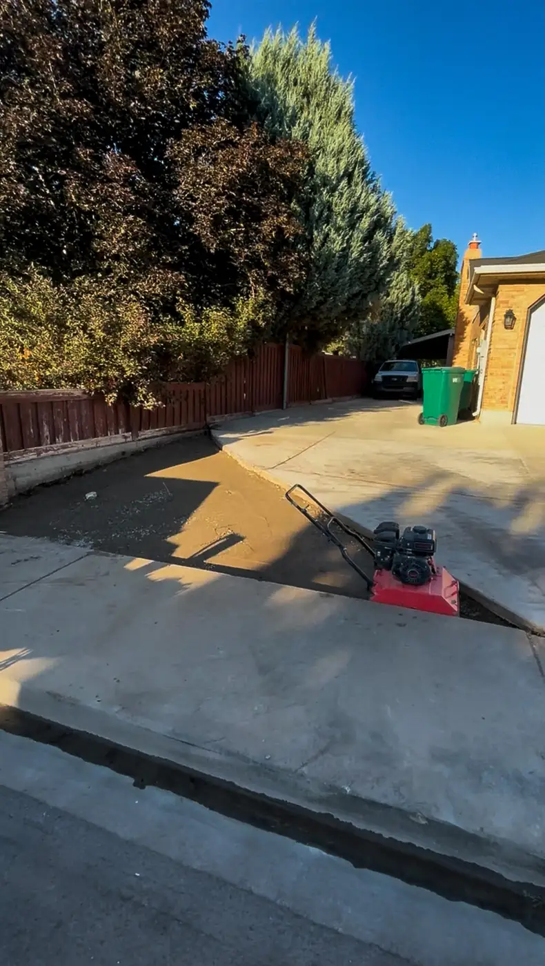 Plate compactor packing gravel base next to a driveway