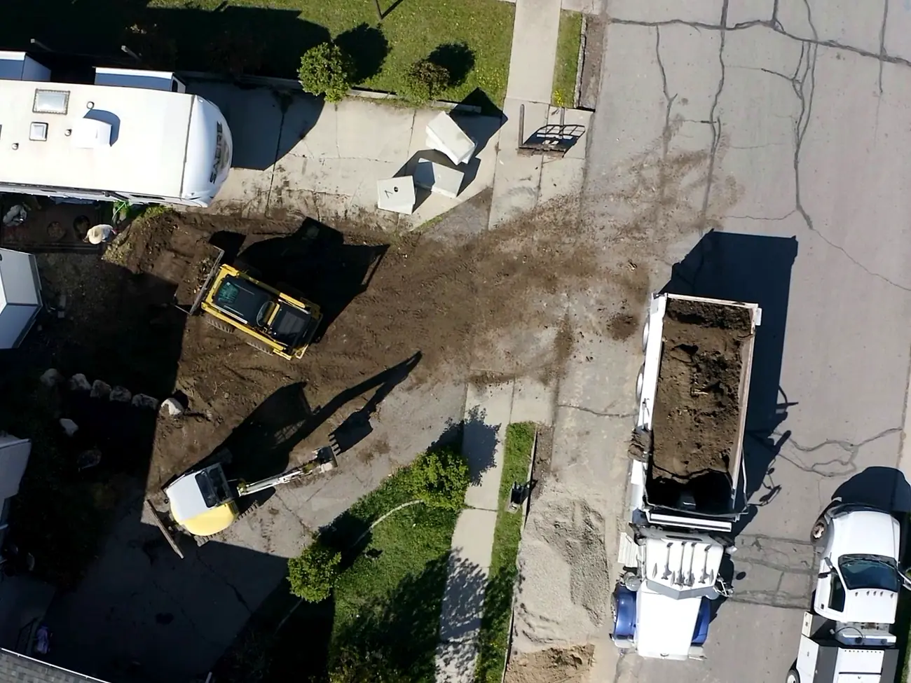 Aerial view of a mini excavator loading a dump truck during a front yard dig-out