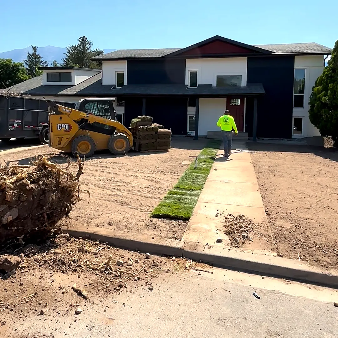 Crew laying sod along the walkway of a new build over a new sprinkler system